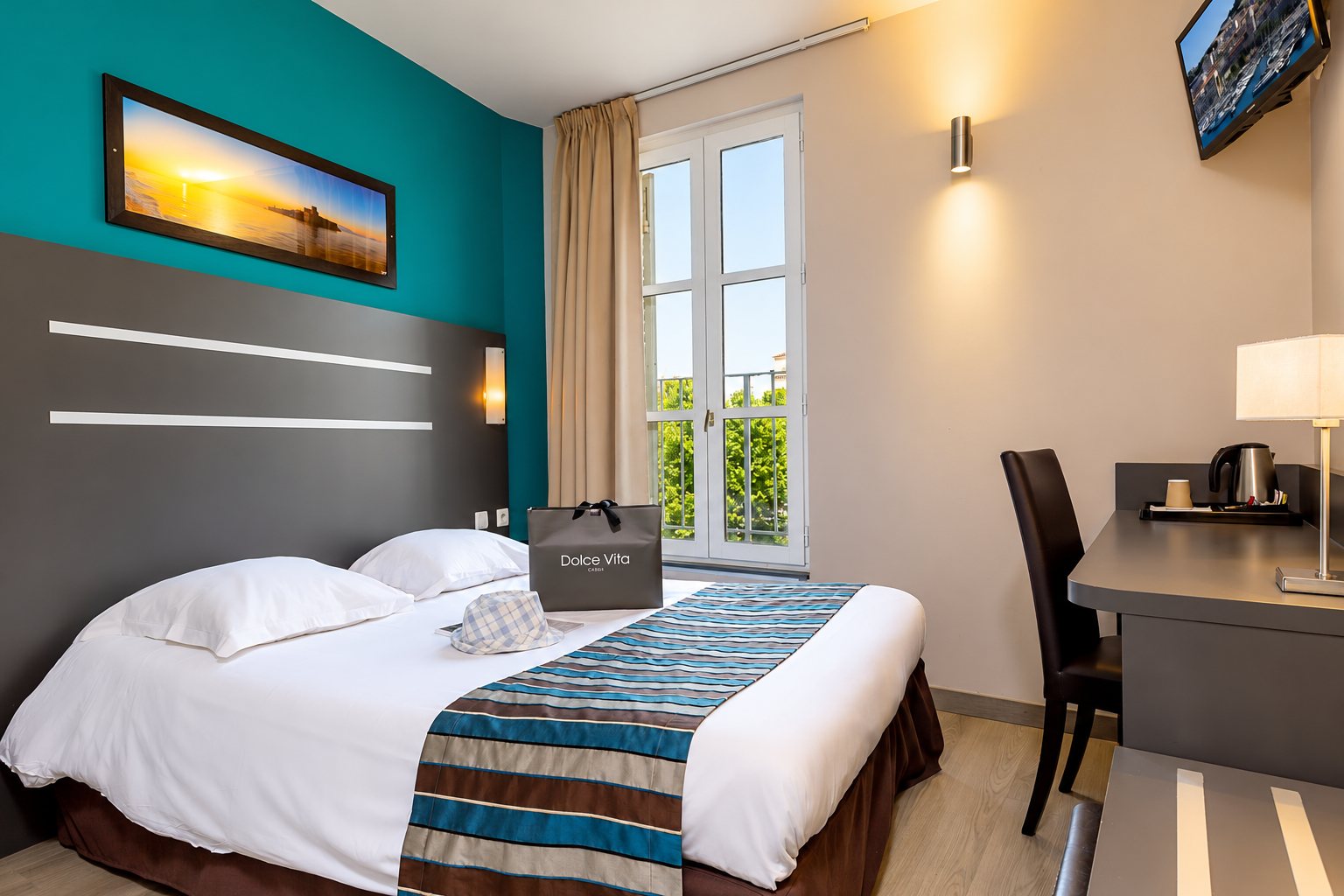 Chambre d'hôtel avec un lit double, un mur turquoise et une grande fenêtre
